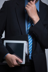 business man holding tablet device in business suit isolated in studio