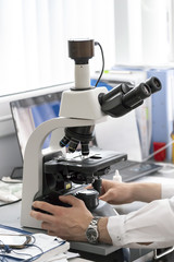 Hands scientist set up a microscope in the laboratory