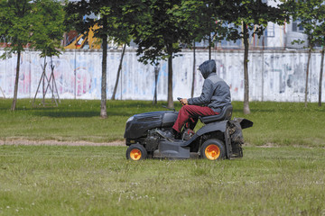 A man on a tractor lawn mower mows the grass