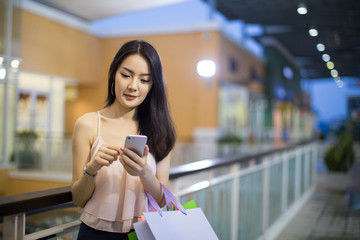 Woman walking and using a smart phone in the street in a sunny summer day..