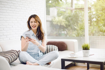 Happy young woman with earphone dancing and listening to music on sofa