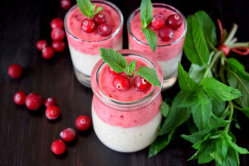 Two layered smoothie with cranberry and banana in a glass jar against the dark background