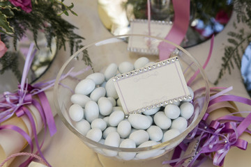 Fototapeta na wymiar Confetti dentro un recipiente di vetro sopra un tavolo decorato per un ricevimento di nozze