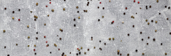 Panoramic view of a gray concrete kitchen countertop with spilled colorful pepper seeds