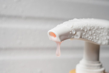 Water drop on liquid soap dispenser pump during bath time