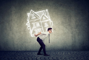 Overburdened business man carrying a house