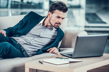 Young bearded businessman in suit lying in office