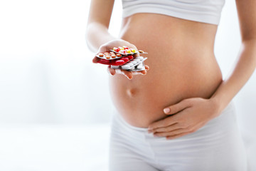 Pregnancy Vitamins And Medications. Pregnant Woman With Pills