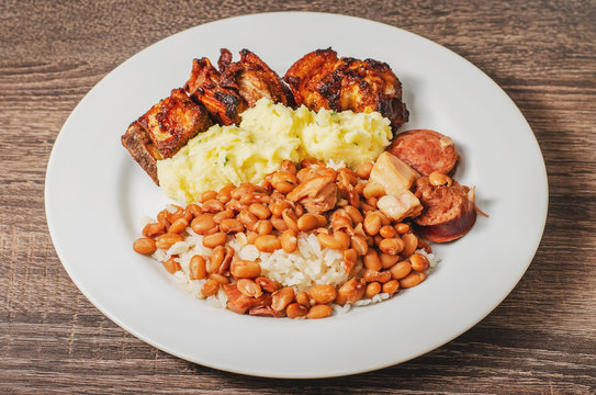 Brazilian cuisine, dish with rice and beans (arroz com feijao) seasoned with sausage and bacon, mashed potatoes and pork (costelinha de porco). White dish, daily typical brazilian food.