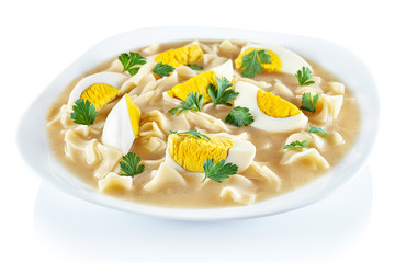 Zurek - polish easter soup with eggs and pasta covered fresh green parsley. Traditional polish sour soup in a white plate on white background