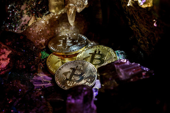 Silver and golden bitcoin in a cave of gem stones