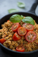 Close-up of couscous with cherry tomatoes, spices and fresh green basil, selective focus