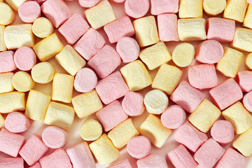 Background from small yellow and pink zephyr close-up. Small candy marshmallow. Top view.