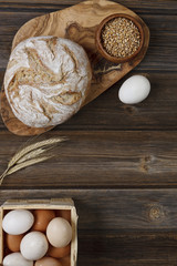 Fresh homemade bread, corn and chicken eggs. Top view, close-up on  vintage wooden background