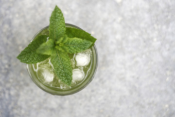 Ein Glas mit einer klaren grünen Flüssigkeit wird mit Eiswürfeln gekühlt und ist beschlagen. ...