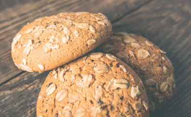 Oatmeal cookies with a sprinkling of oat flakes and seeds on a wooden background