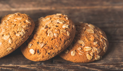 Oatmeal cookies with a sprinkling of oat flakes and seeds on a wooden background
