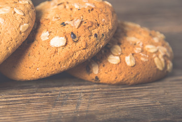 Oatmeal cookies with a sprinkling of oat flakes and seeds on a wooden background