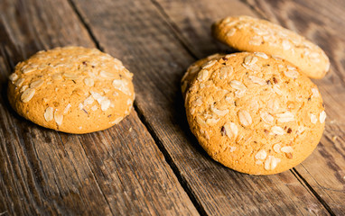 Oatmeal cookies with a sprinkling of oat flakes and seeds on a wooden background