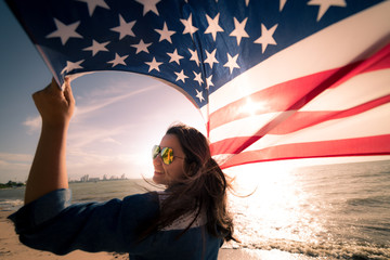USA Independence day, 4 July. Close up oung happy woman holding United States of America flag and...
