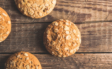 Oatmeal cookies with a sprinkling of oat flakes and seeds on a wooden background