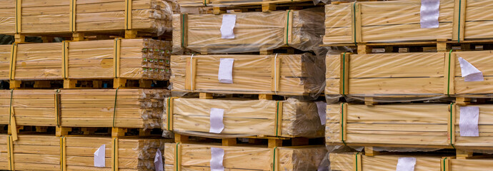 many packages of wooden boards, lumber in film, with labels