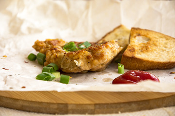 Fresh fried pork chops sprinkled with green onions and ketchup.  Arrangement  on the wrapping paper