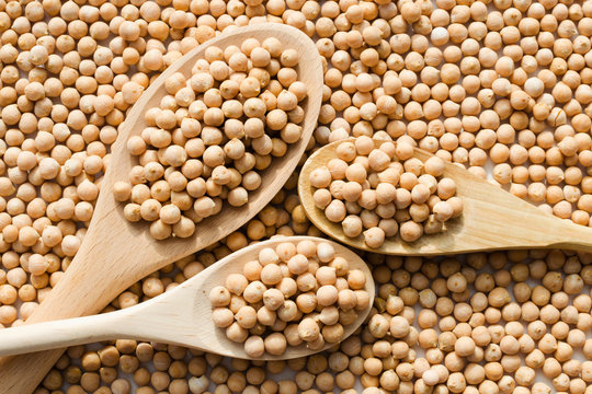 dry raw chickpeas in wooden spoons
