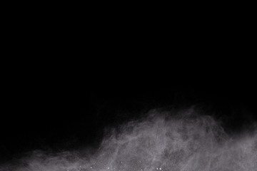 Fototapeta na wymiar Freeze motion of white dust explosion on black background. Stopping the movement of white powder on dark background. Explosive powder white on black background.