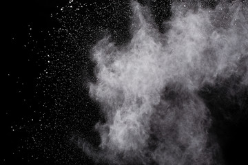  Freeze motion of white dust explosion on black background. Stopping the movement of white powder on dark background. Explosive powder white on black background.