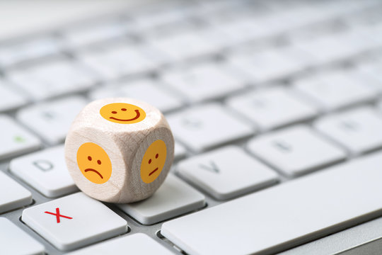 verschiedene Emoticons auf einem W&uuml;rfel der auf einer Tastatur liegt
