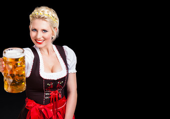 attraktive junge Frau im Dirndl mit Bierkrug vor schwarzem Hintergrund