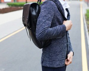 Fashion man. Cheerful young smiling businessman with backpack enjoying walk the city.