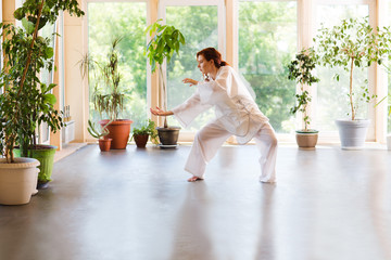 Young Woman praticing tai chi chuan in the gym. Chinese management skill Qi's energy.