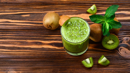 Healthy fresh kiwi smoothie in glass on a wooden background