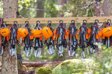 Gardinen Climbing gear equipment - orange helmet harness zip line safety equipment hanging on a board. Tourist summer time adventure park family and company team building concept for extreme recreation sports © echobg