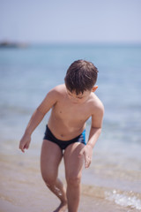 Adorable young kid sitting in the water on the beach