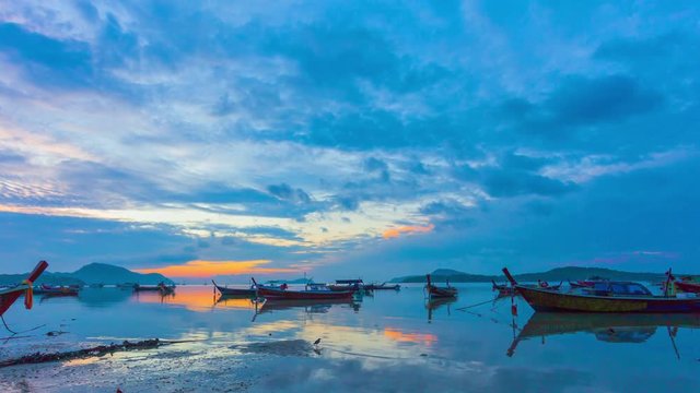 time lapse sunrise above fishing boats in Rawai sea during high tide