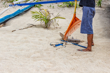 An employee is cleaning the beach. Rake for a tool to get hay from the sea and garbage disposal...