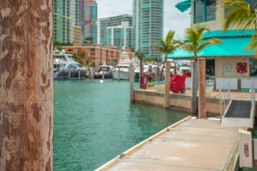 Fototapeta na wymiar Wooden post. Expensive, luxurious yachts and tall buildings in the background. Miami, Florida, USA