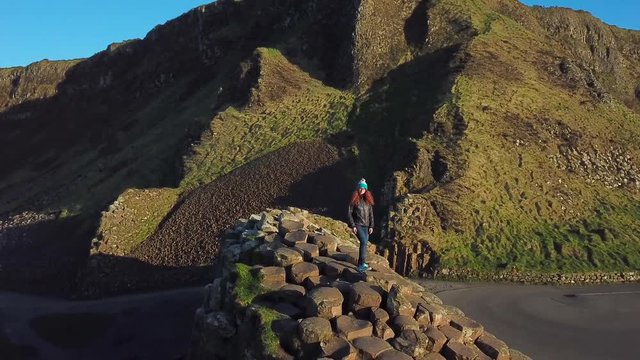4k Aerial Shot of female enjoying the view on Giant's Causeway rocks in Northern Ireland