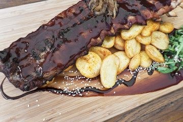 barbecue spare ribs served on a wooden board with side dishes