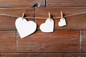 White paper hearts hanging on wooden background