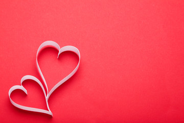 White paper hearts on red background