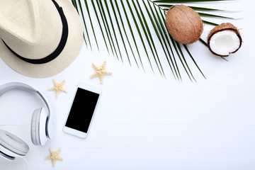 Coconuts with smartphone and palm leaf on wooden table