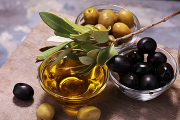 Bottle virgin olive oil and oil in a bowl with some olives