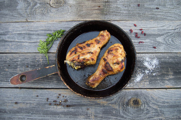 Grilled chicken legs with spices and herbs on apan on a wooden b