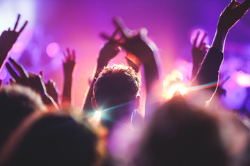 A crowded concert hall with scene stage lights, rock show performance, with people silhouette and...