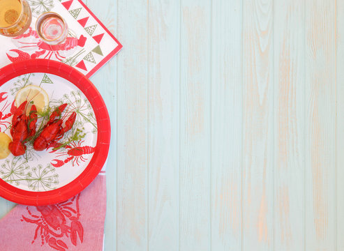 Red boiled crayfish with twig of dill on the white plate, wooden rustic table . Two snaps glass of liquor with salt on edge, white vine. Traditional Finnish Crawfish fest, napkin crawfish