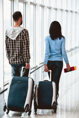 Fototapeta na wymiar White young couple with suitcases at airport